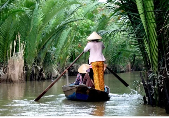A small boat traveling through a palm-lined canal in Viet Nam